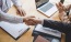 people shake hands over a work table