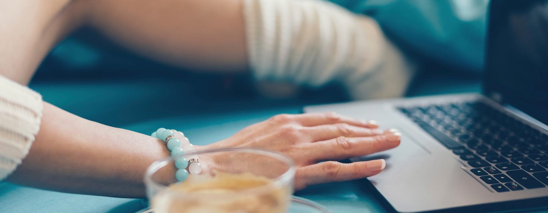 woman on a laptop next to a cup of coffee